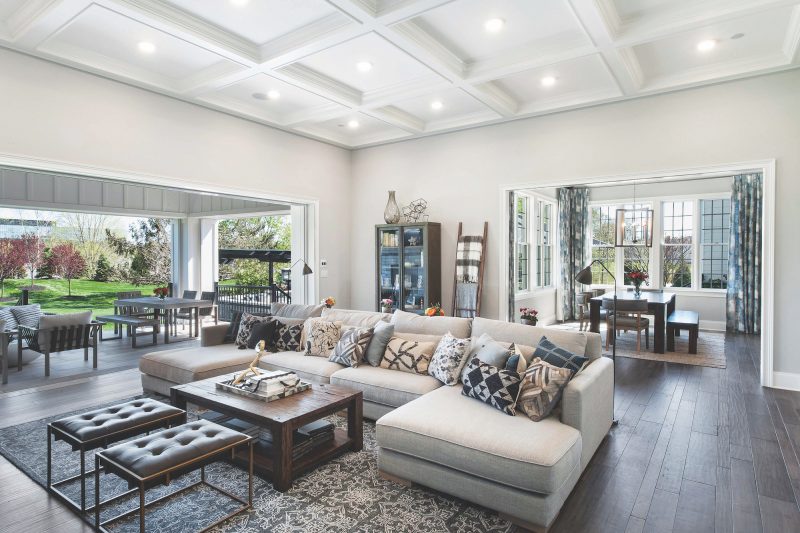 Living room with white beam ceiling, open floor plan, dark hardwood floors, and tan L-shaped sofa