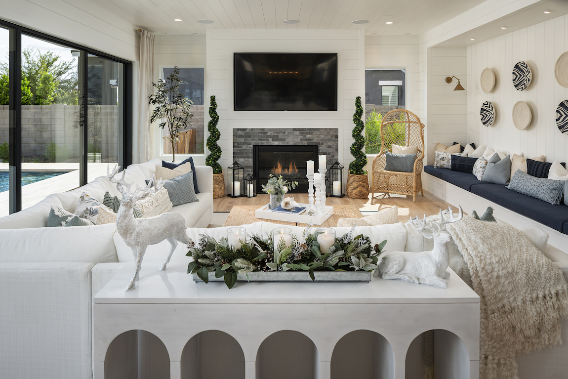 Living room with shiplap walls, white sofas, fireplace and green holiday Christmas decor with wicker chair. 