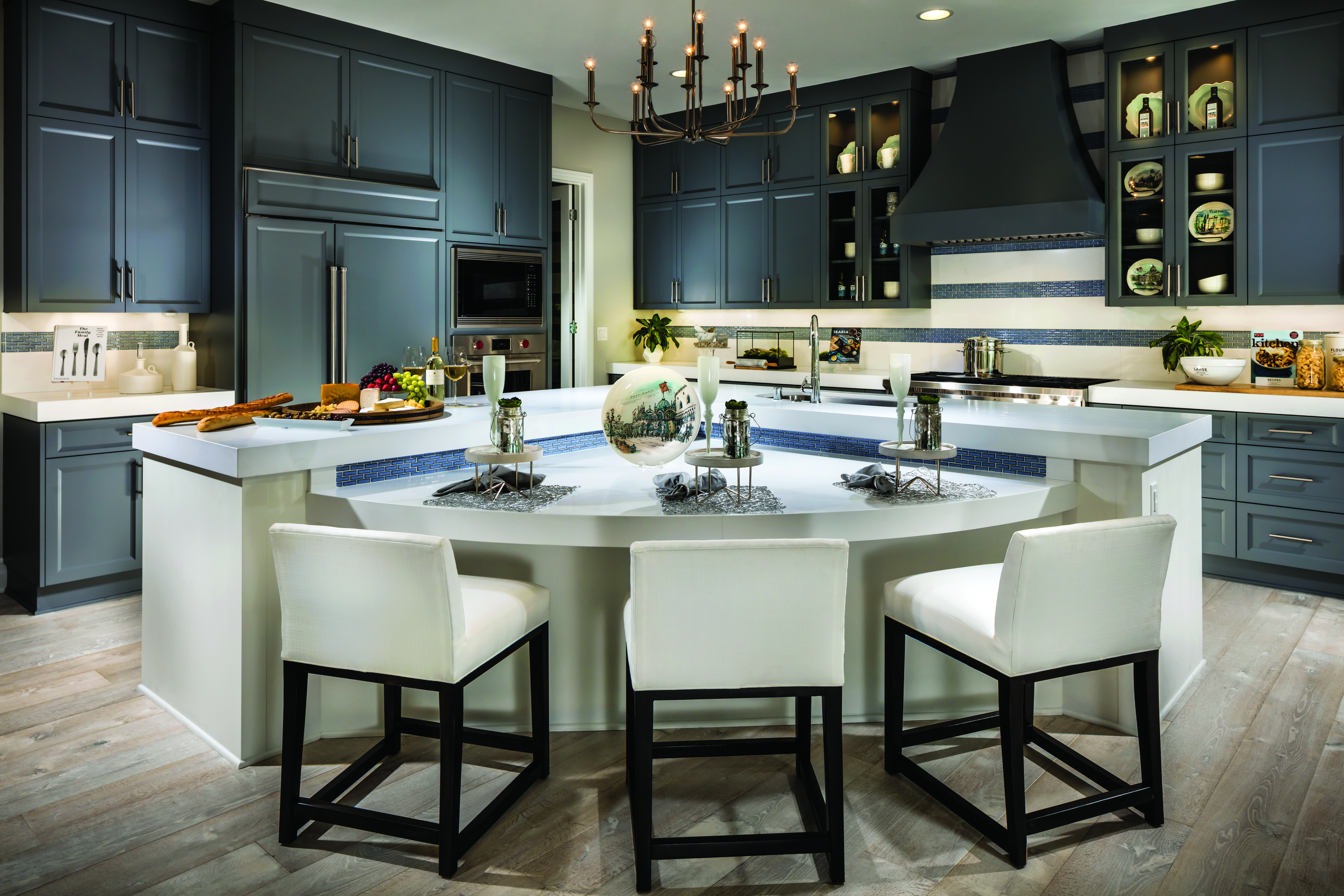 Kitchen with grey cabinets and bar stools around a center island.