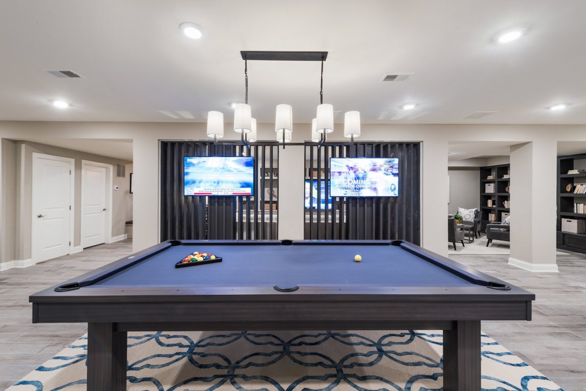 Basement with a pool table and television.