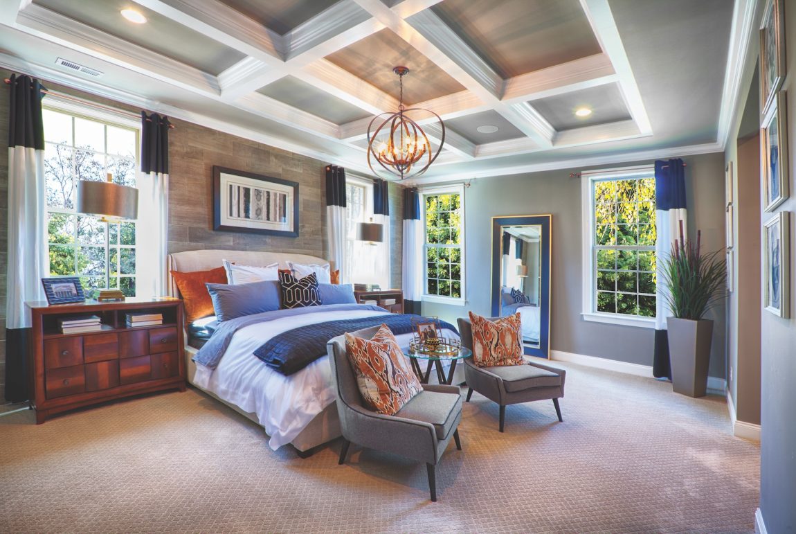 Bedroom with ceiling beams, light fixture and colorful comforter