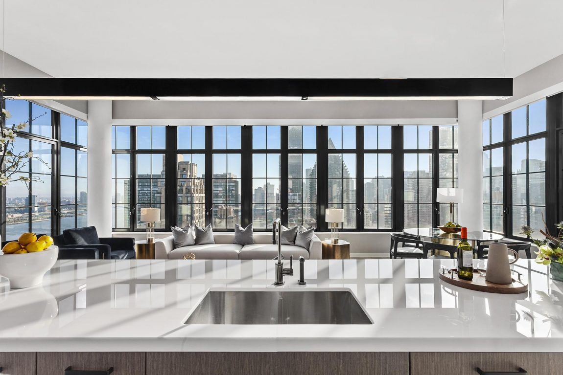 A kitchen island, seating area, and windows allowing for a panoramic view of the city.