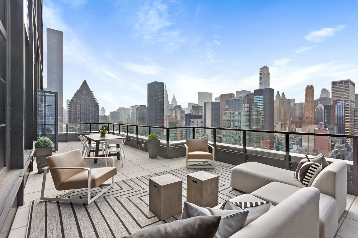 An outdoor terrace with a dining table and lounge area overlooking the cityscape