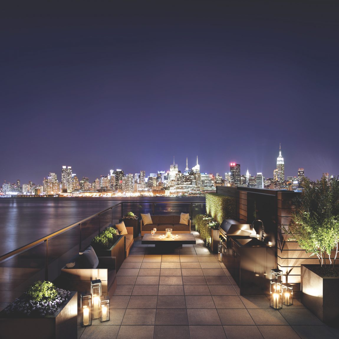 A patio with a fire pit overlooking New York City at night from across the river.