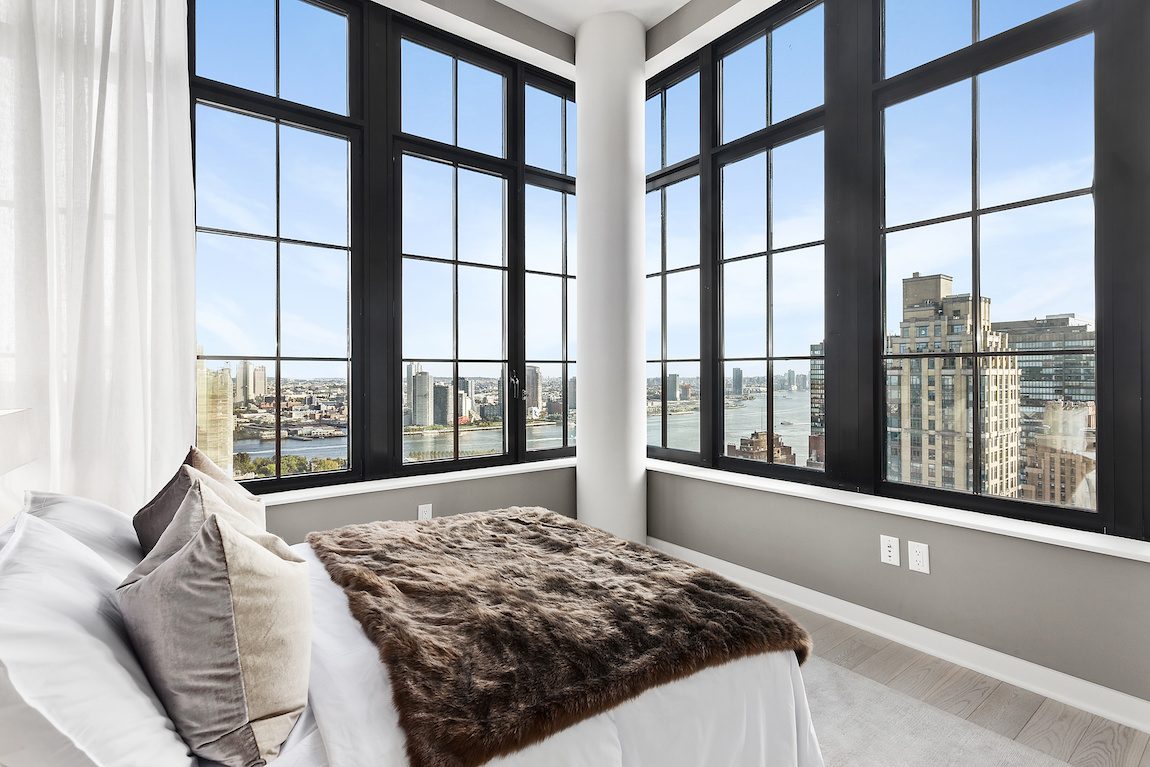 Bedroom with black trimmed windows overlooking New York City