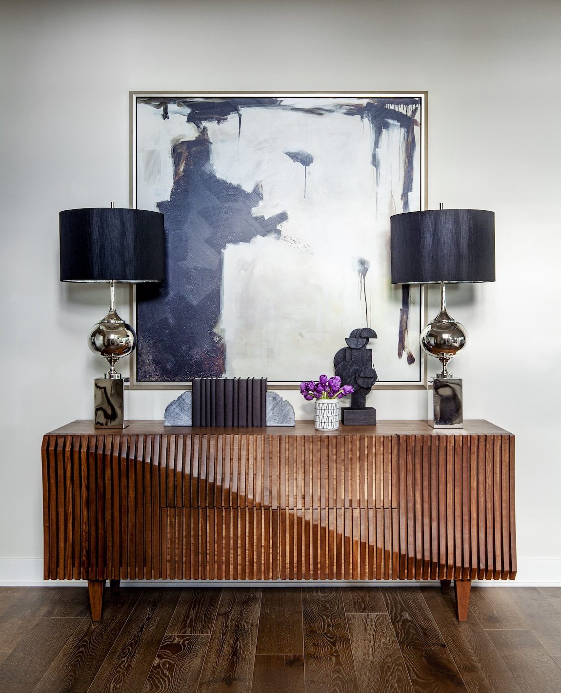 Hallway with brown table and lamps with black shades. 