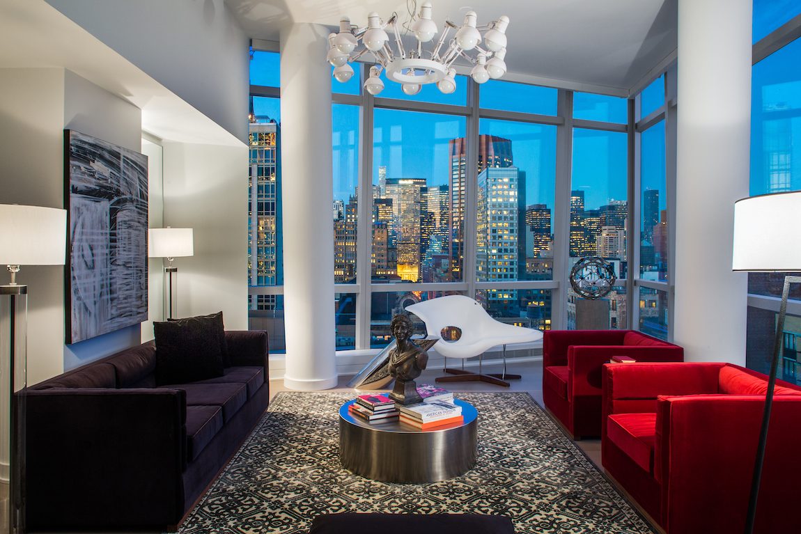 Living room with red velvet chairs and black sofa with view of New York City