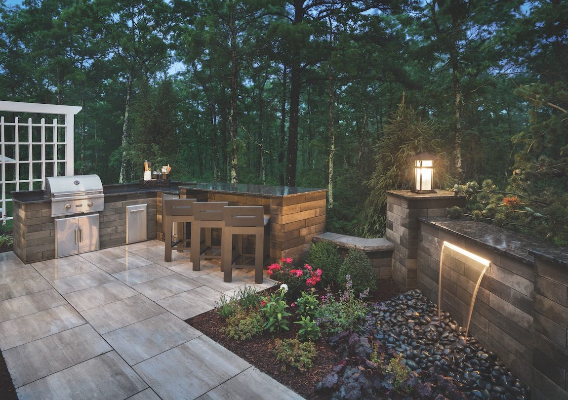 Outdoor kitchen with waterfall and landscaping.