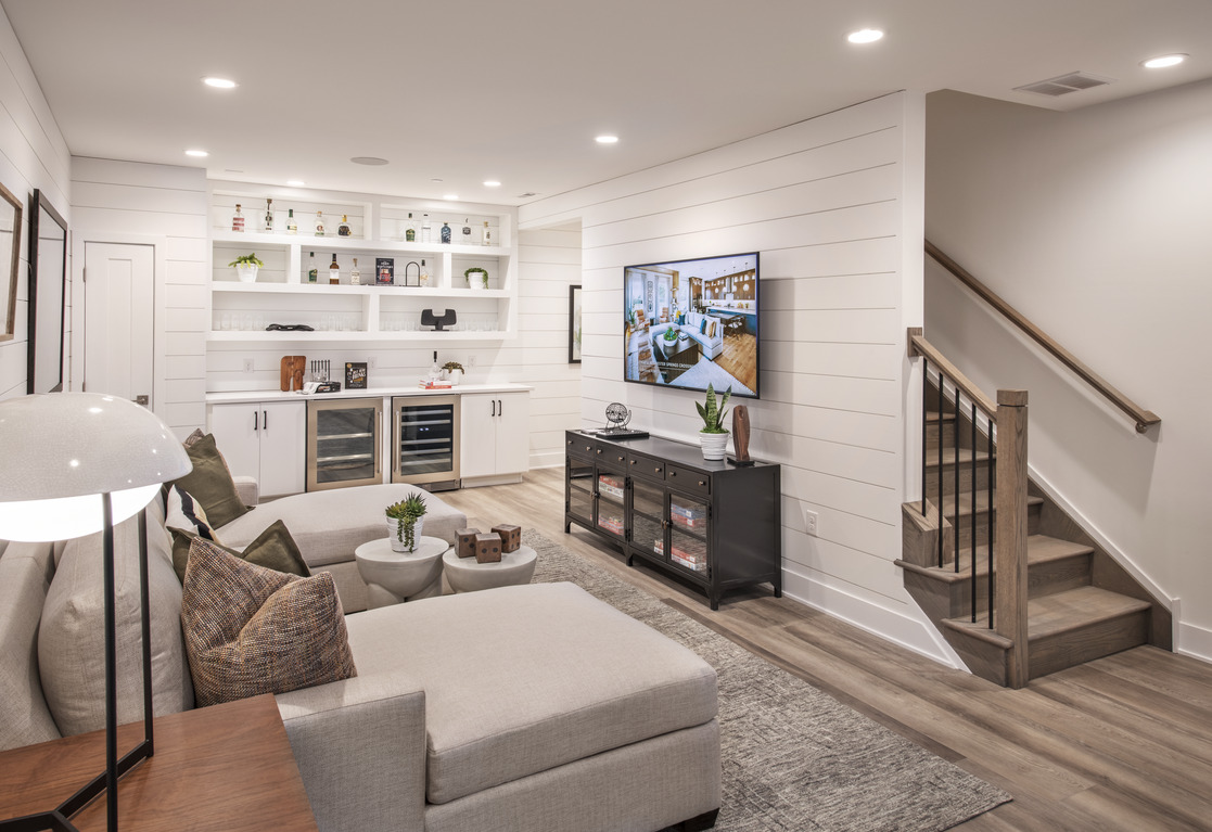 White basement with entertainment system, wine display, and couches