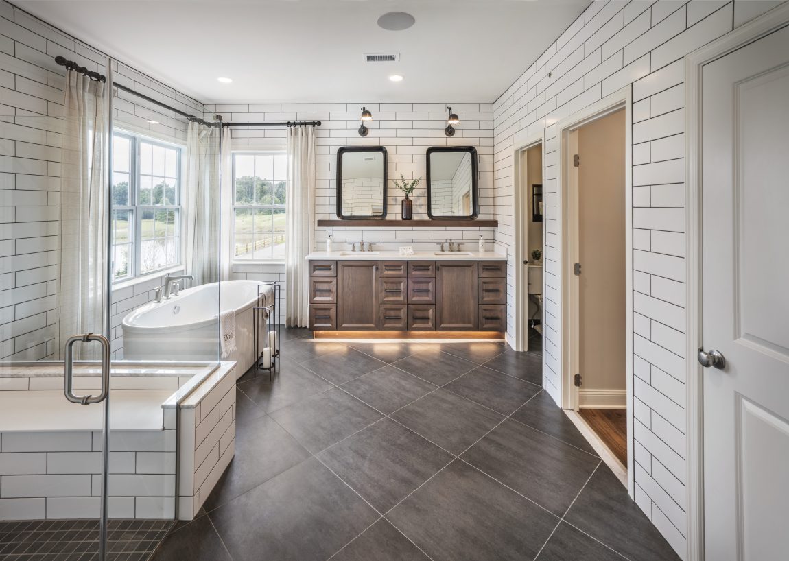Bathroom boasting dual-sink vanity, freestanding bathtub, and walk-in shower with seating.
