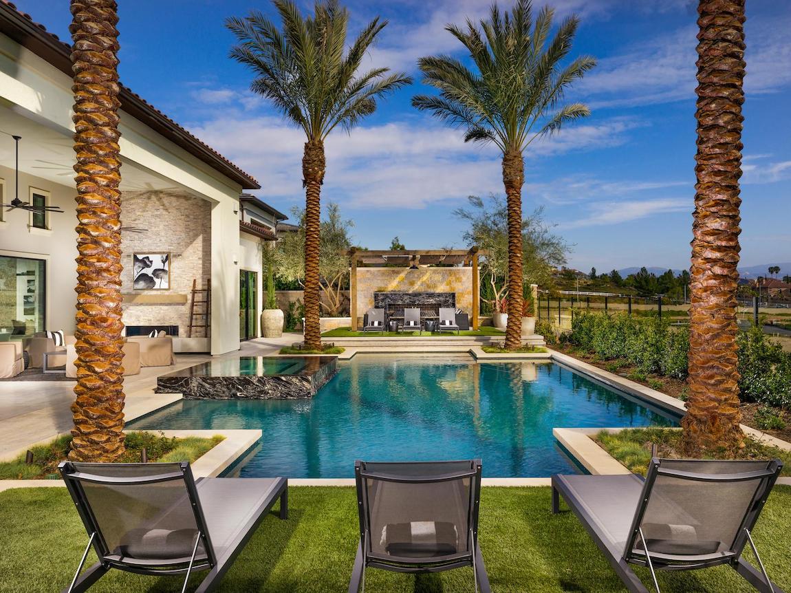 Pool and jacuzzi with lawn chairs, fireplace, and outdoor bar. 