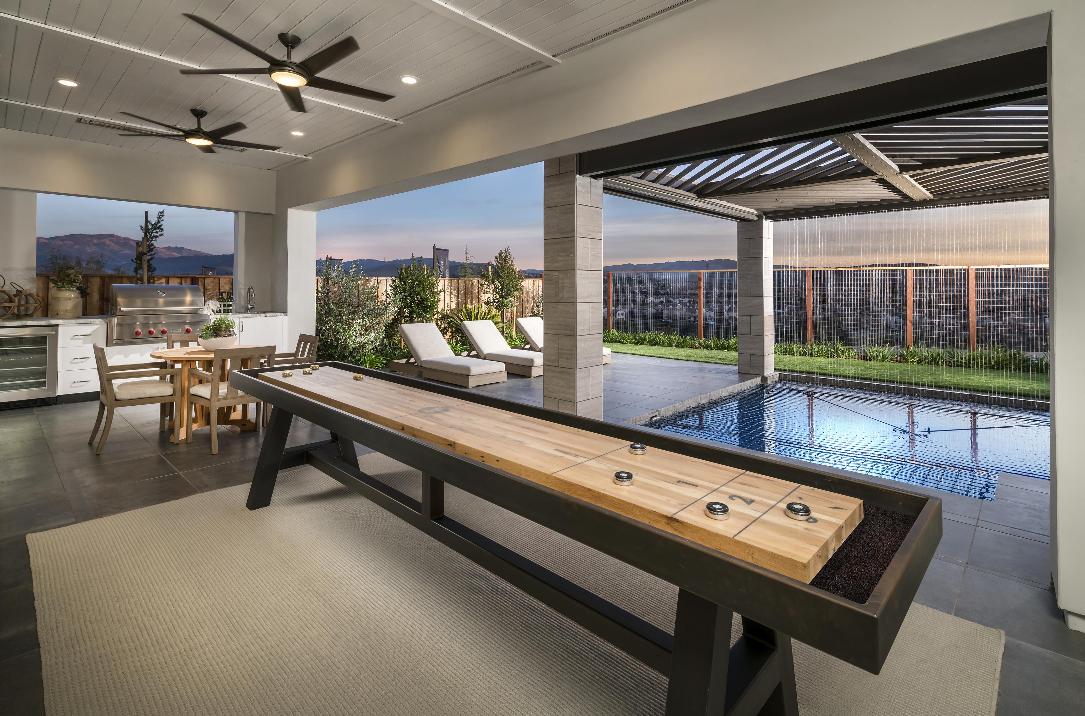 Entertaining outdoor living space highlighted by pool, grilling area, and shuffleboard.