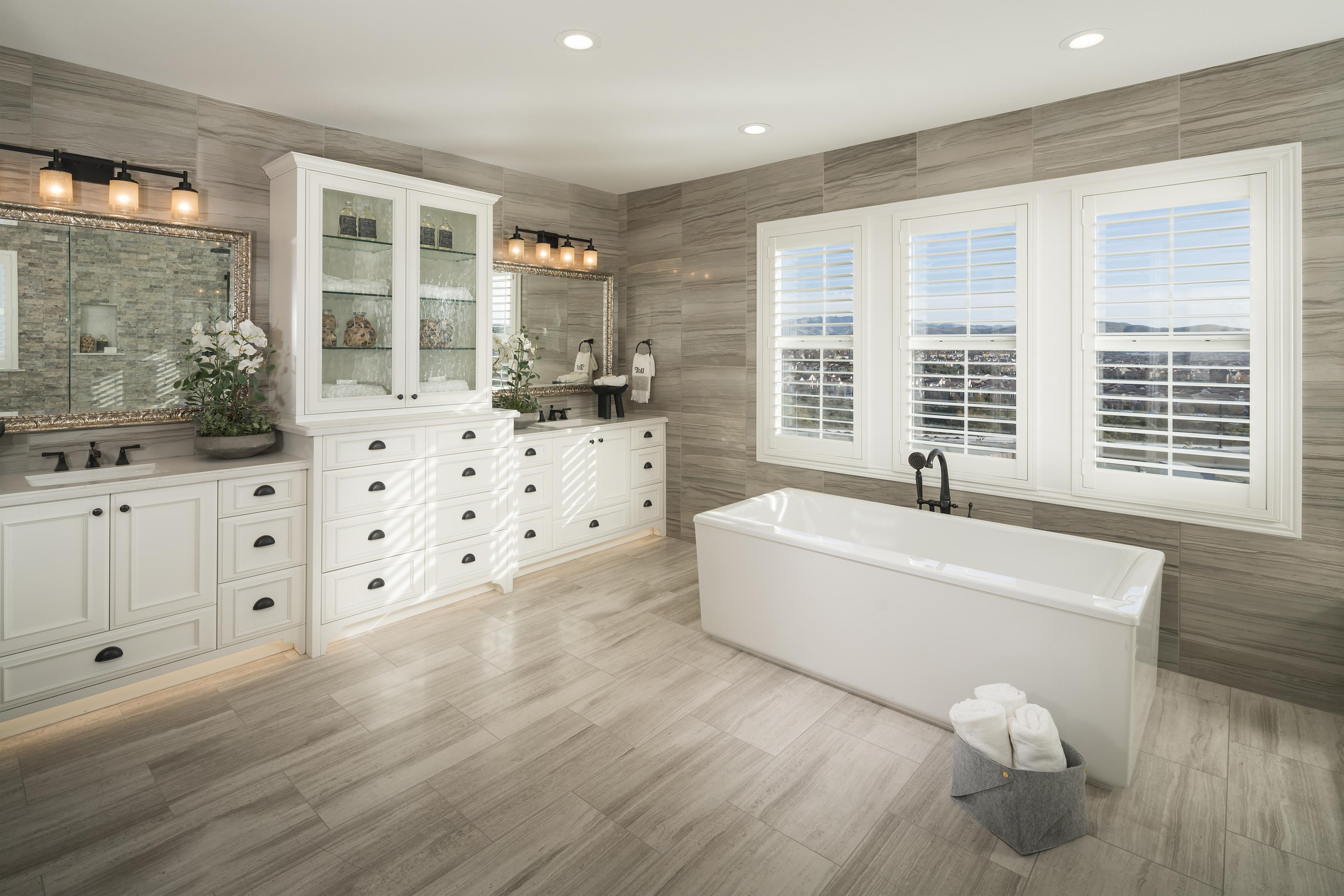 Bathroom with impressive freestanding bathtub, dual vanities, and white cabinetry.