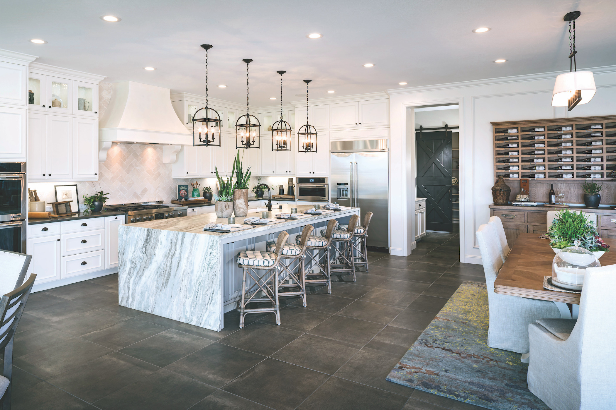 Open-concept kitchen featuring large marble island and matching pendant lighting.