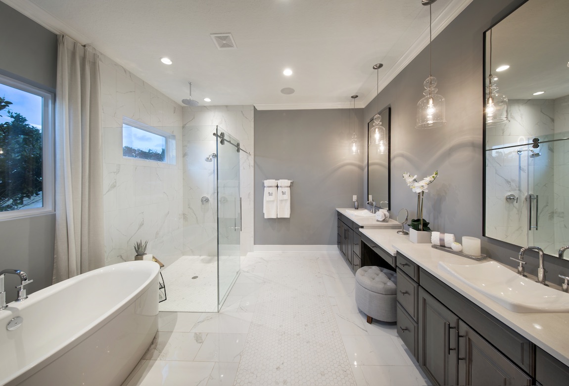 White bathroom with marble shower and tile flooring.