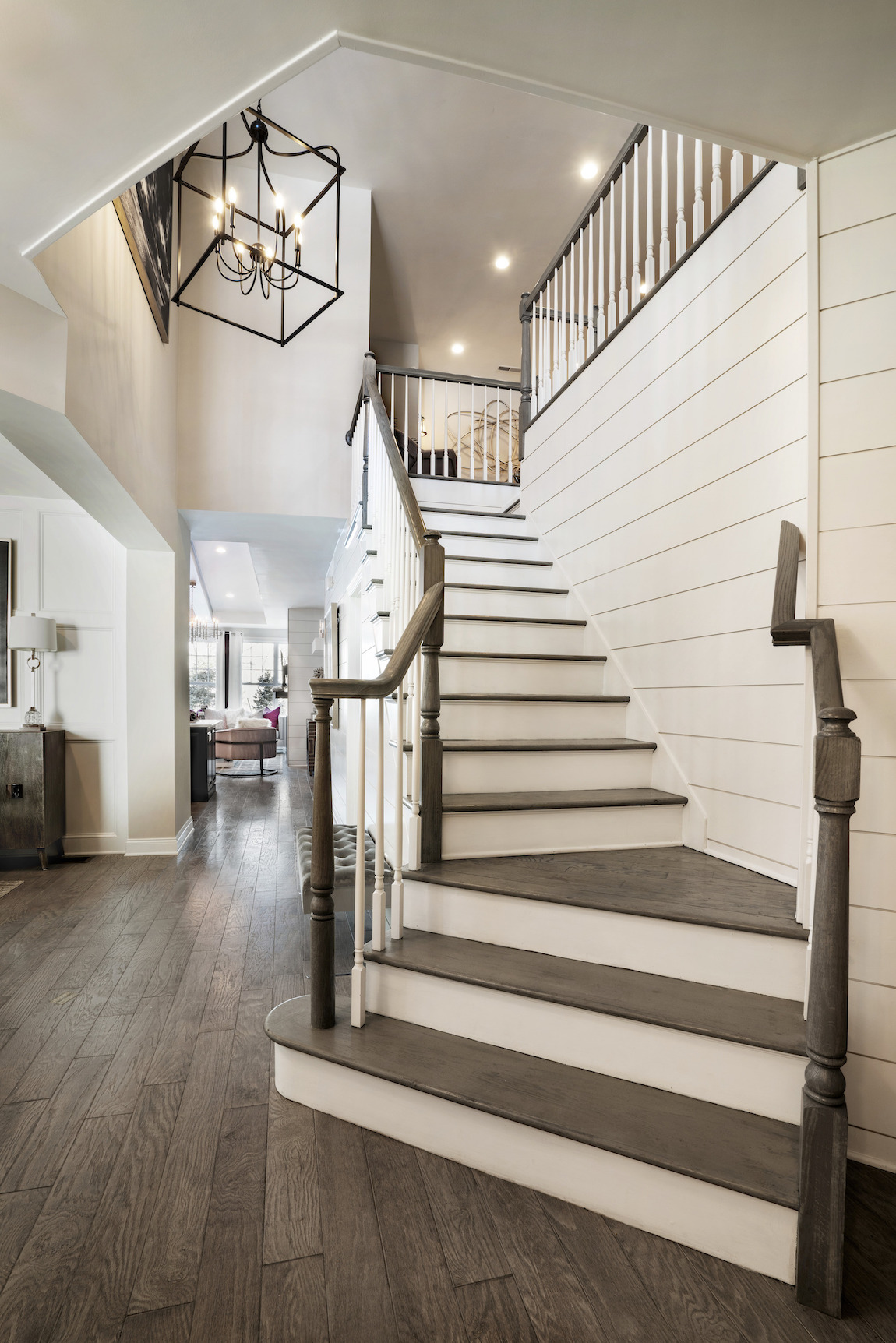 Curved staircase with shiplap siding in a foyer.