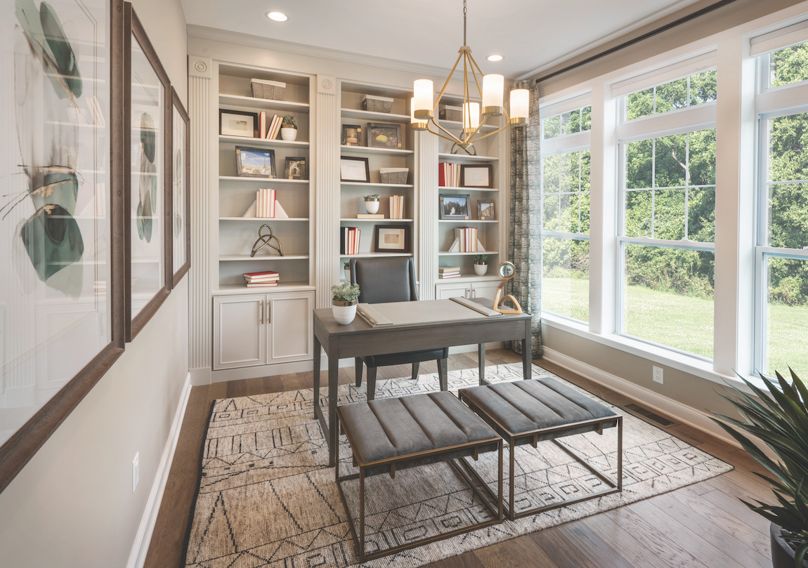 Study with luxurious office furniture, ample natural light, and focal chandelier