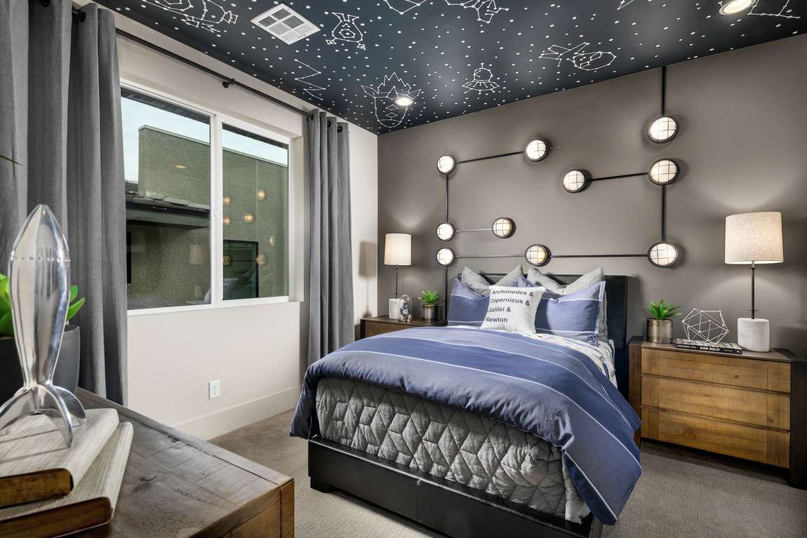 Space themed bedroom with purple comforter, starry night sky ceiling wallpaper and globe accent light fixtures on wall