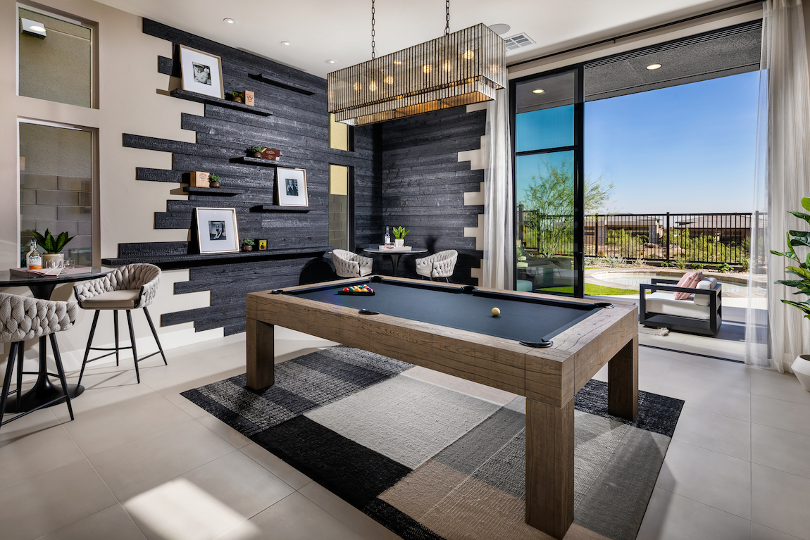 Game room with pool table, accent wall and gold chandelier with backyard view