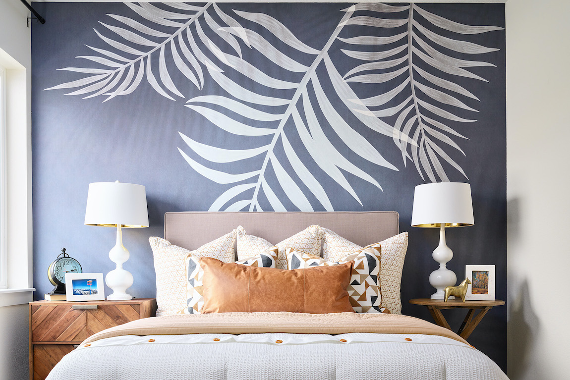 Bedroom with tropical leaf mural wallpaper with brown leather pillow and bed lamps