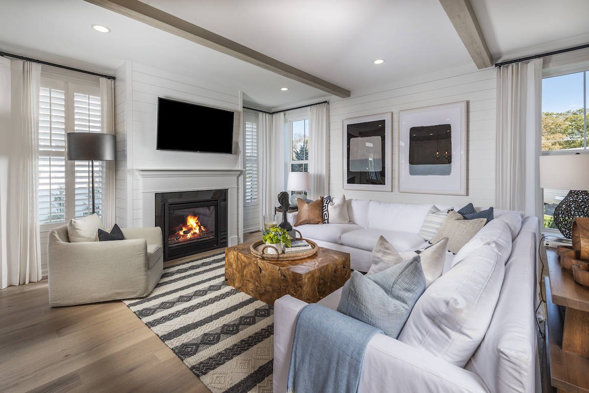 Fireplace with white walls and white couch with black and white striped rug.