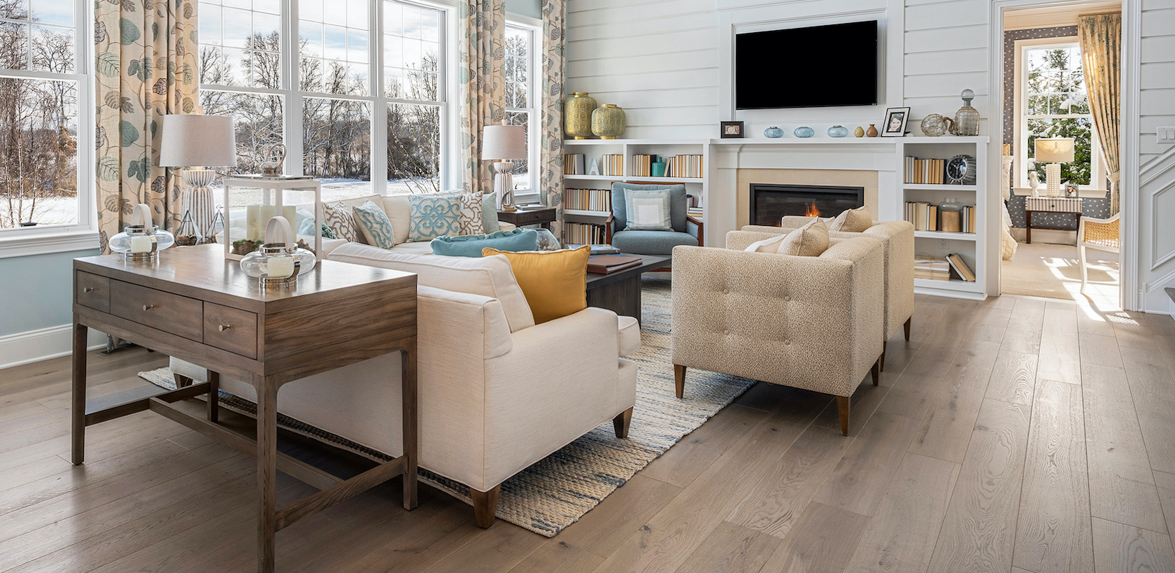 Great room with floor to ceiling windows, light hardwood floors and pastel blue paint colors.