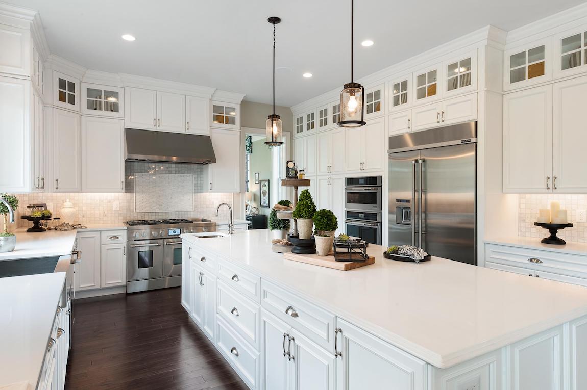White kitchen with island, wall to floor cabinets and dark floors.