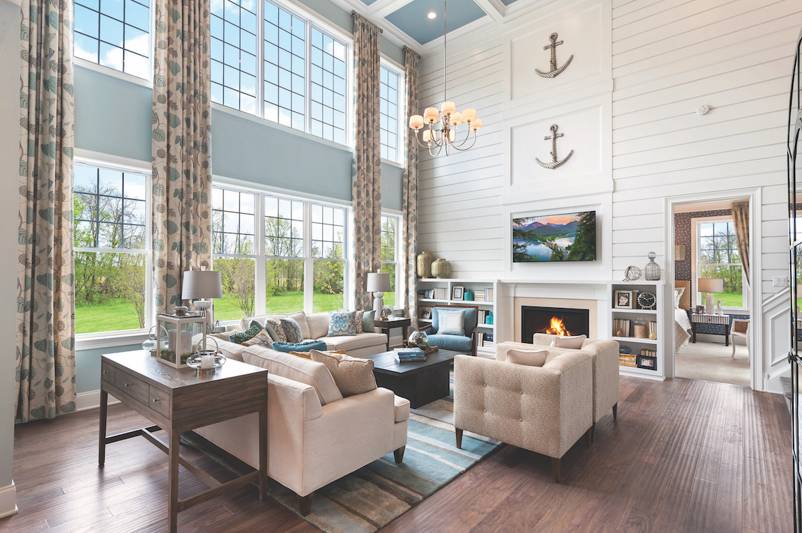 Great room with shiplap accent wall, light wooden floors and window wall.