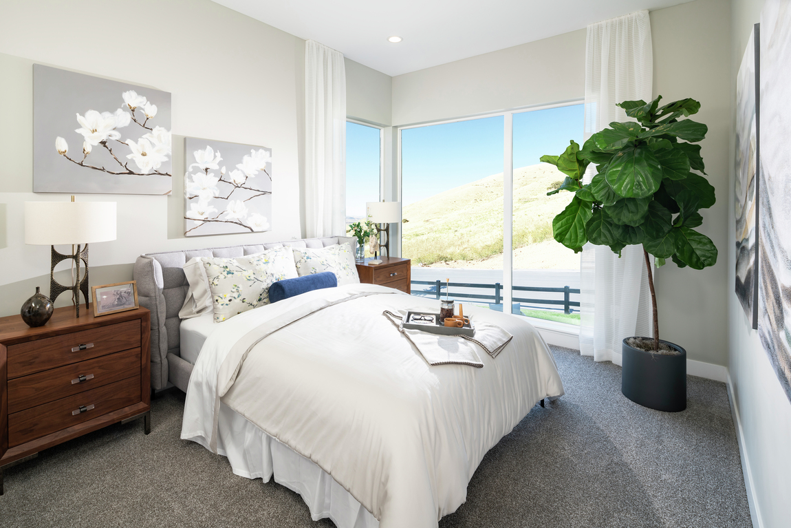 Simple bedroom with white walls and view of mountains.