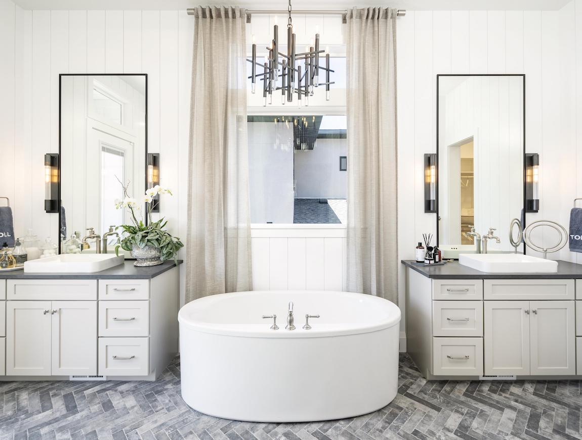 Bathroom with circular tub and dual vanities with modern light fixture.