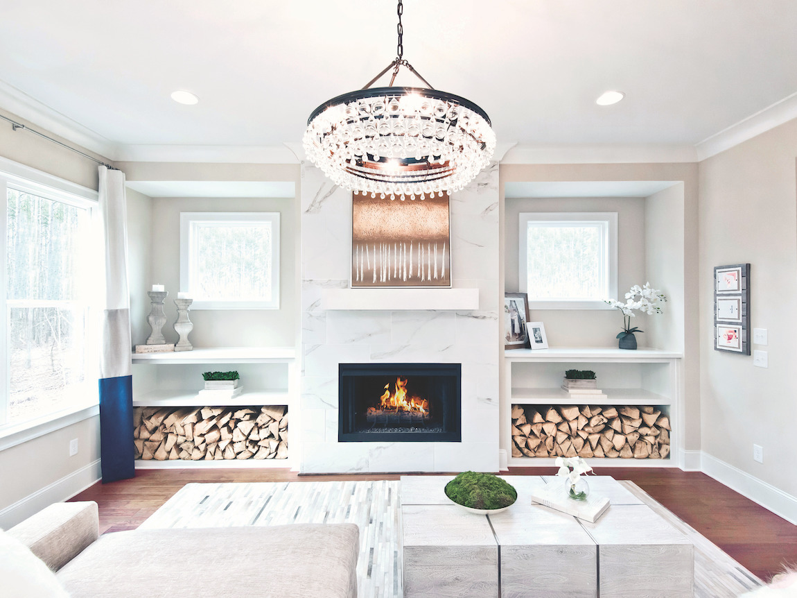 Luxury great room with accent wall, built-in shelving, and striking chandelier