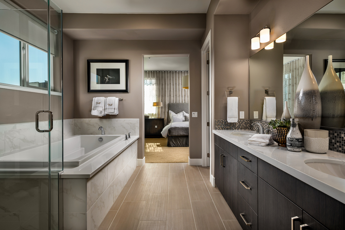 Bathroom with metal finishes, brown painted walls, square bathtub and quartz countertop.