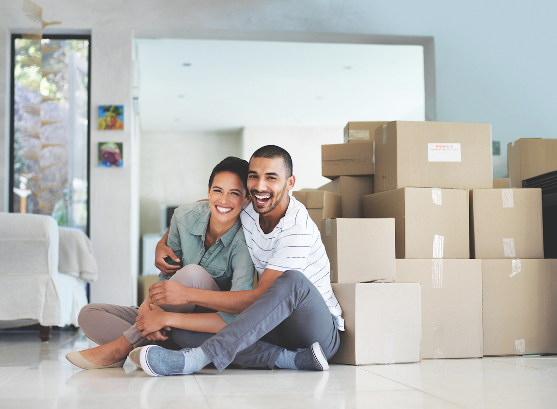 Couple in front of packed boxes moving into new home