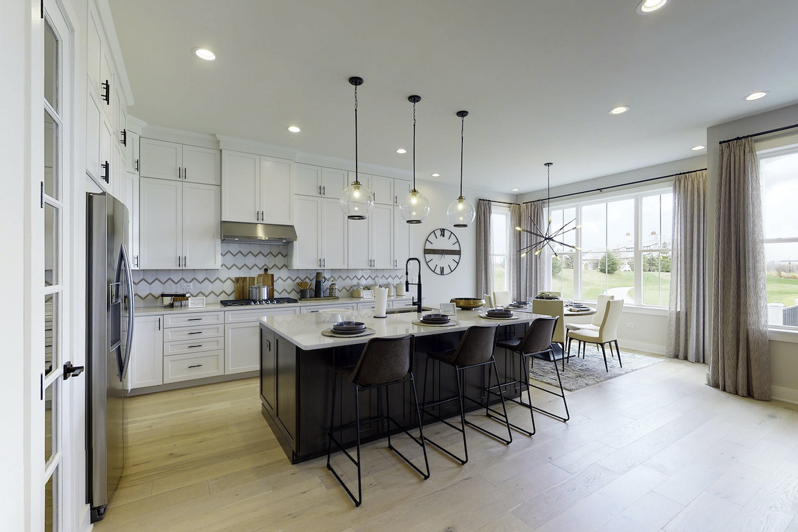 Kitchen with pendant lighting, white cabinets and black island with wooden chairs
