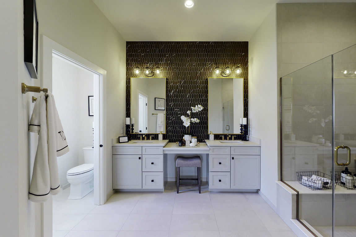 Dual vanity with gold mirrors and textured accent wall