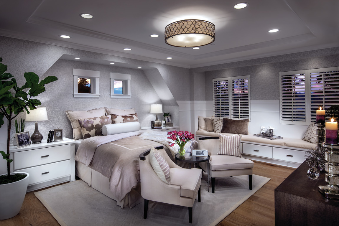 Grey bedroom with rose hues and circular lighting fixture with reading bench