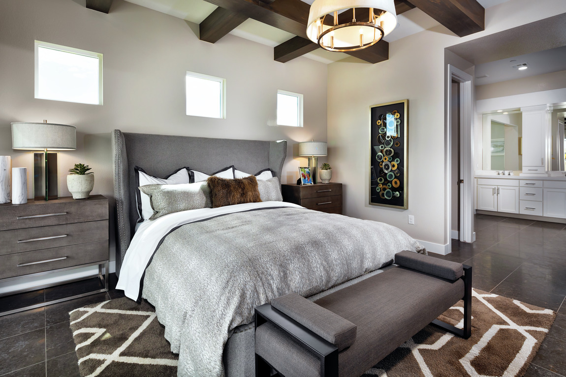 Bedroom with dark wood beams, white and brown pattered rug with modern lighting fixture
