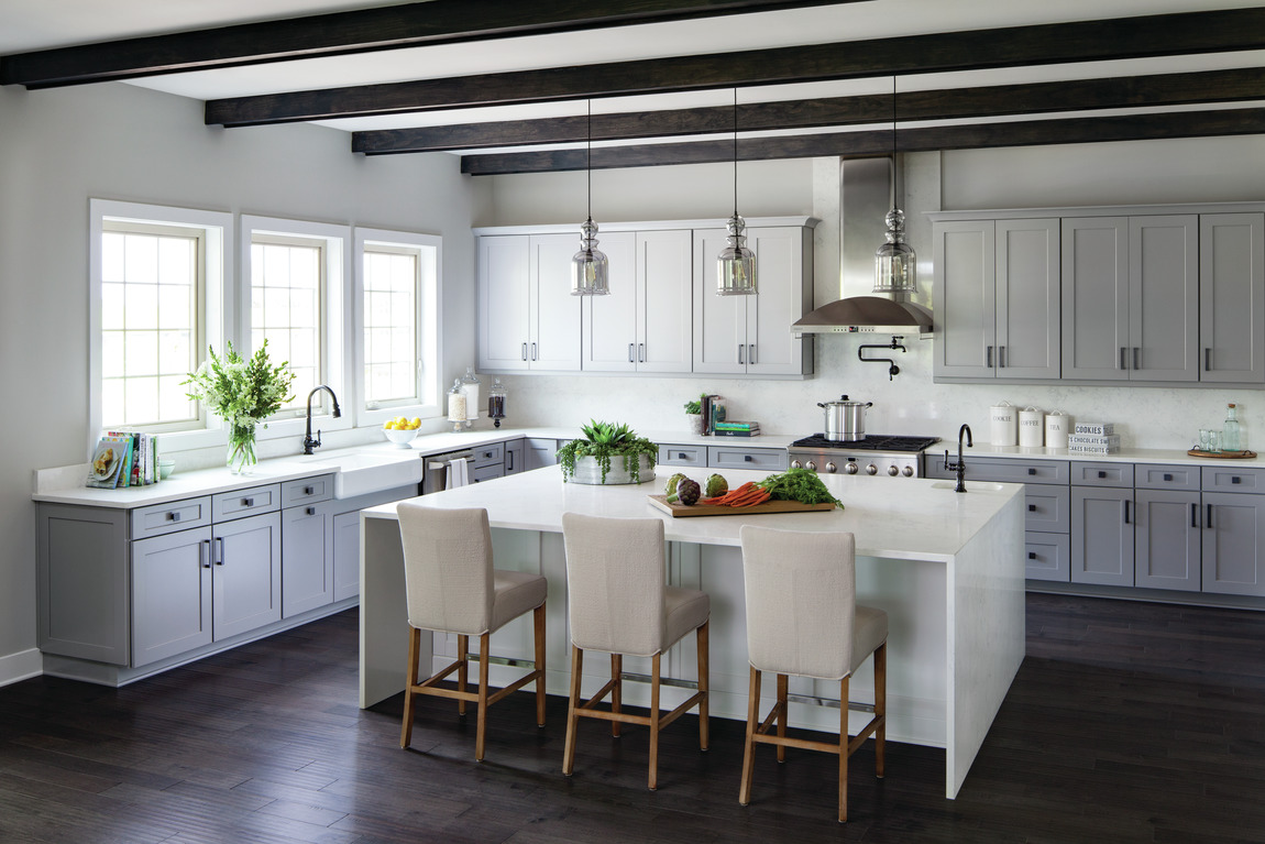 Kitchen with wooded beams on ceiling, white quartz waterfall island and dark hardwood floors