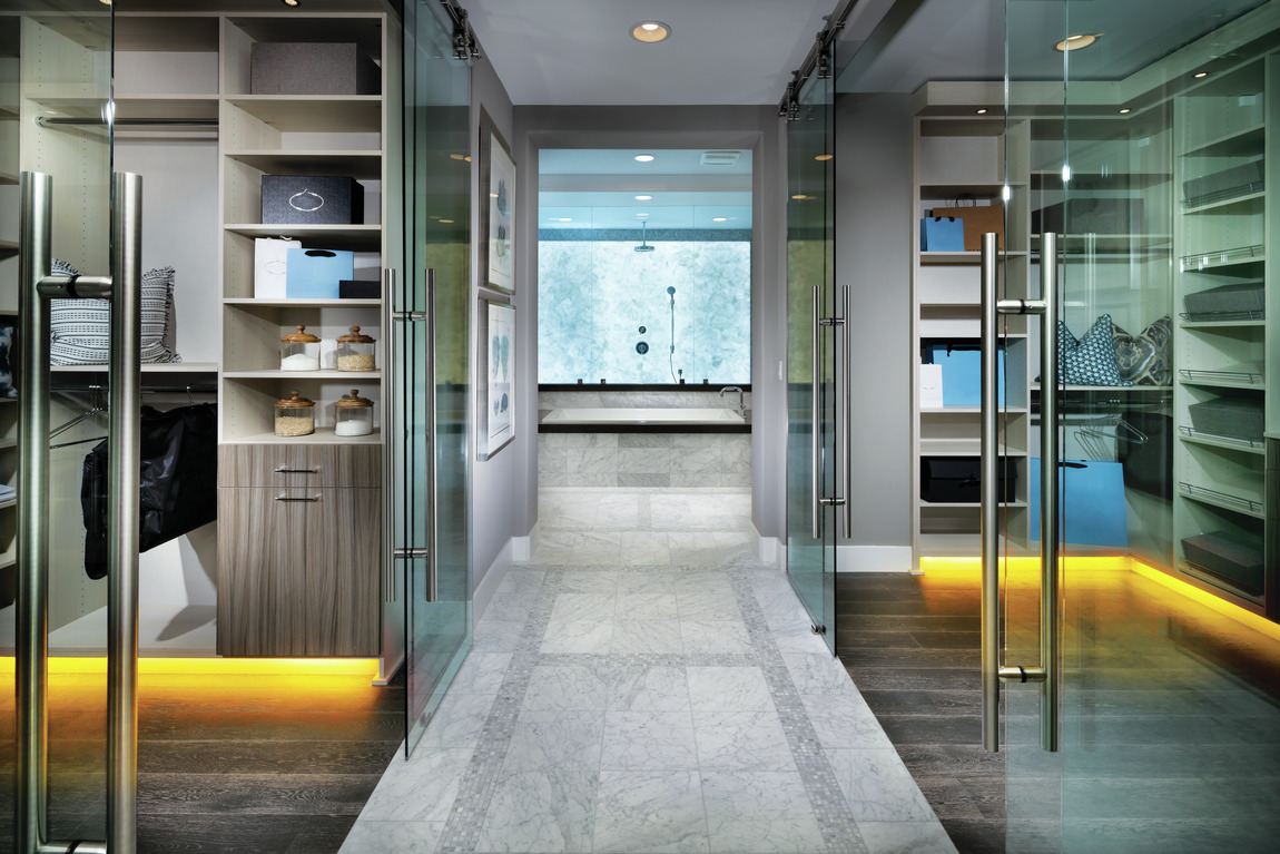 Clear glass closet doors with accent toe-kick lighting and wooden modern flooring