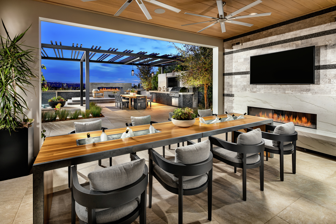 Outdoor living area with patio chairs, wooden table, fireplace and dual fans