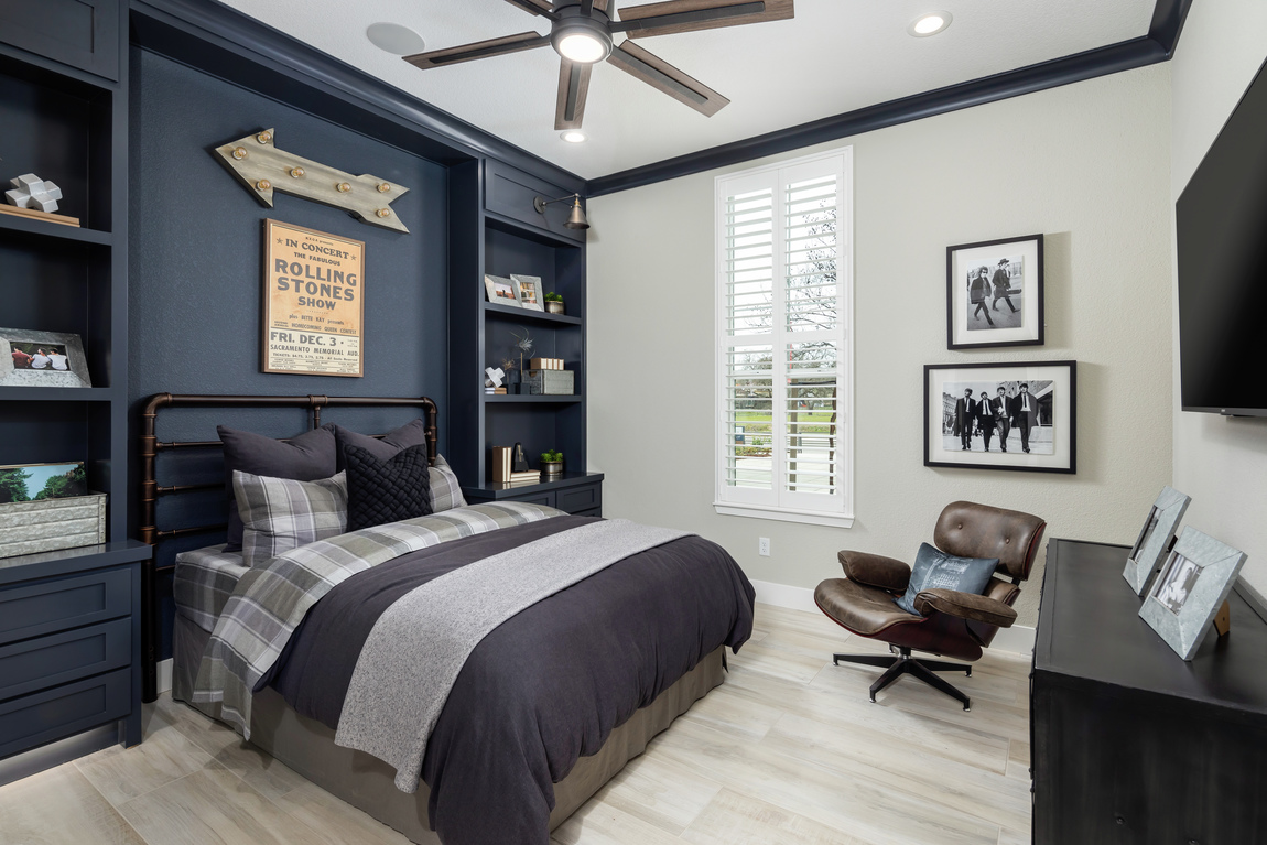 Bedroom with blue accent wall and built-ins with 5 blade ceiling fan