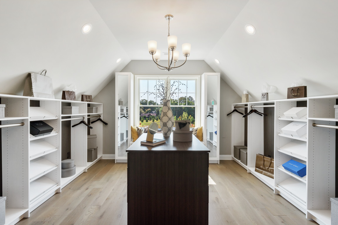 Closet in attic space with arched ceiling and natural lighting
