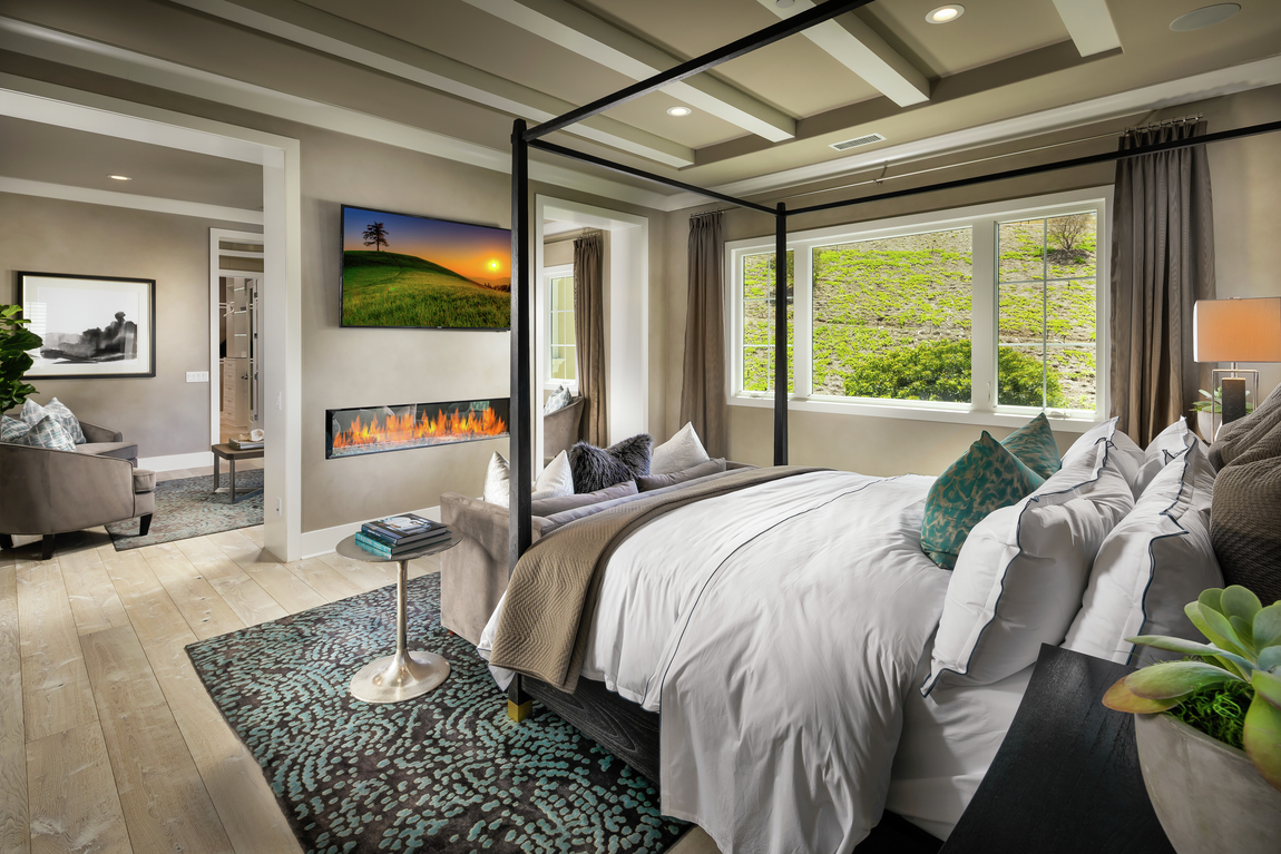 A primary bedroom with a fireplace in front of the bed.