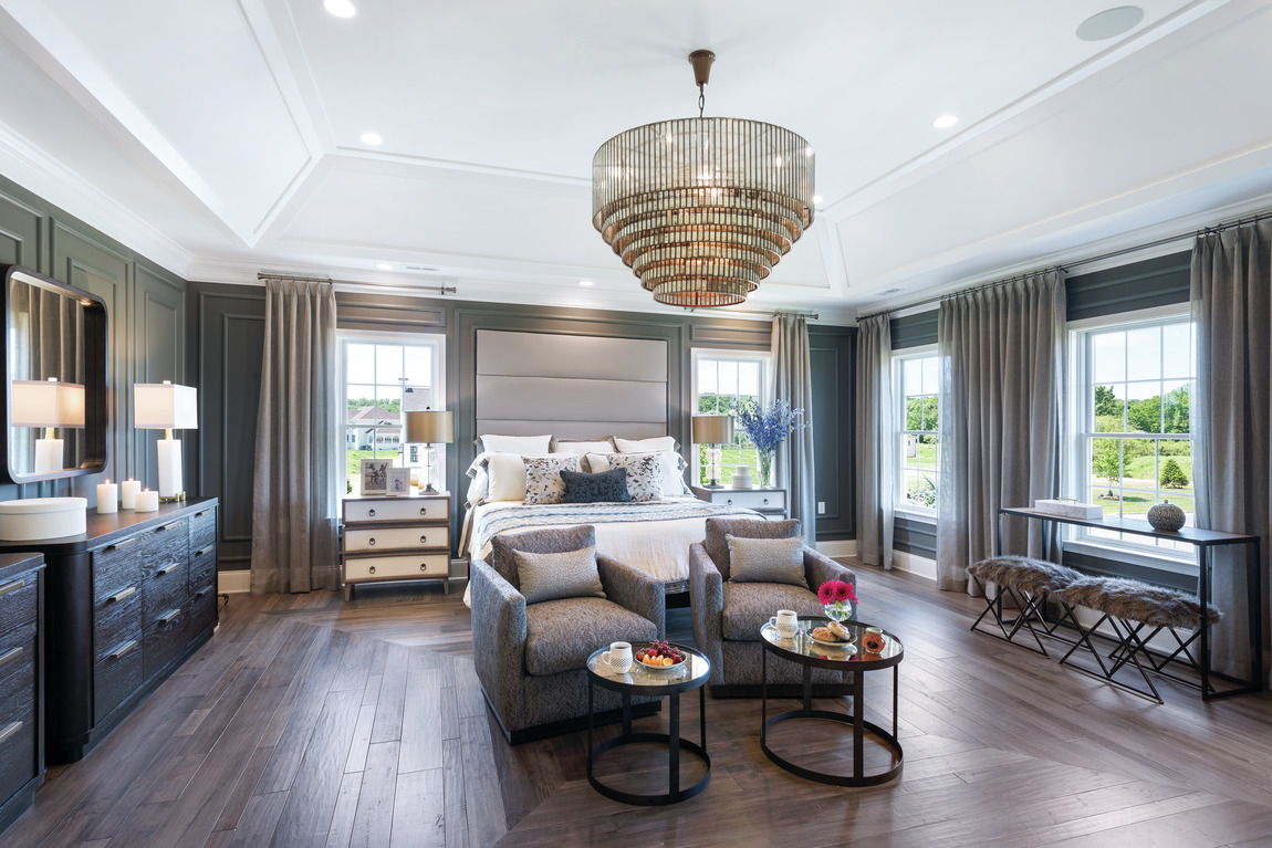 A bedroom with a large chandelier and four windows for natural lighting.