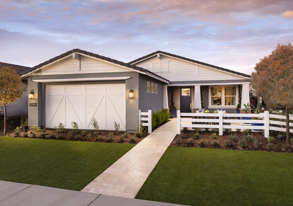 Exterior of a small home with prominent trim over the garage and the gables.