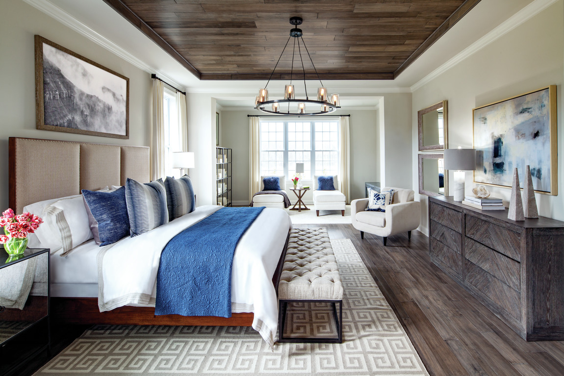 A large bedroom with a separate sitting area and a bench at the foot of the bed.