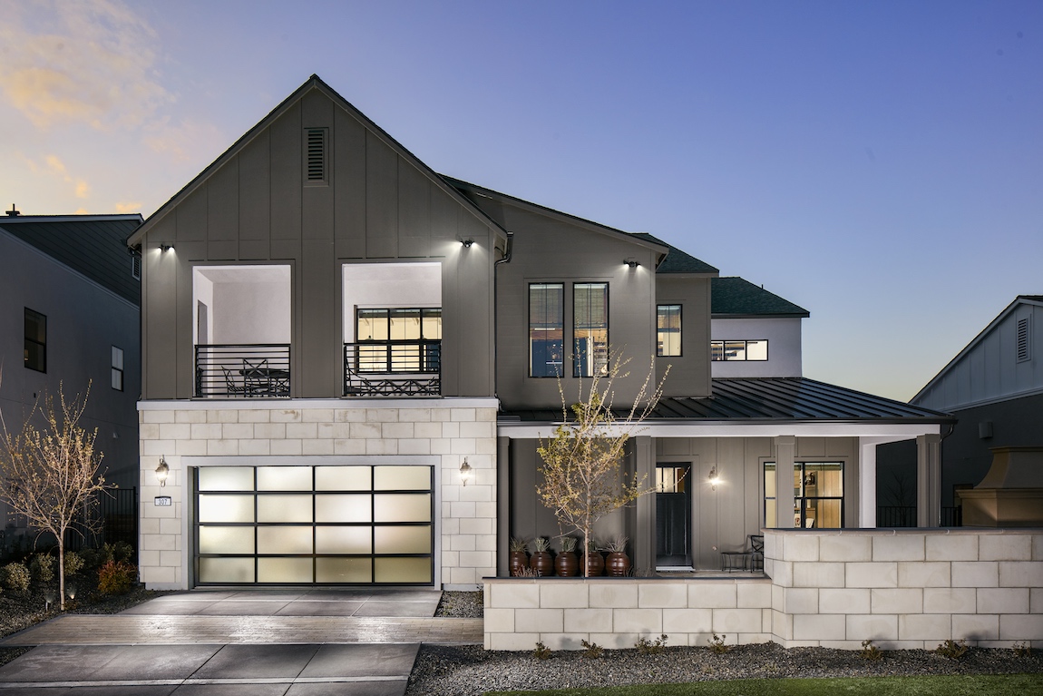 Exterior of a luxury home with a lit up driveway.