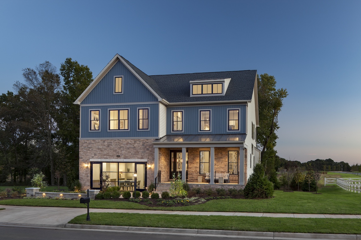 A luxury home photographed from the exterior with warm lighting throughout the home.