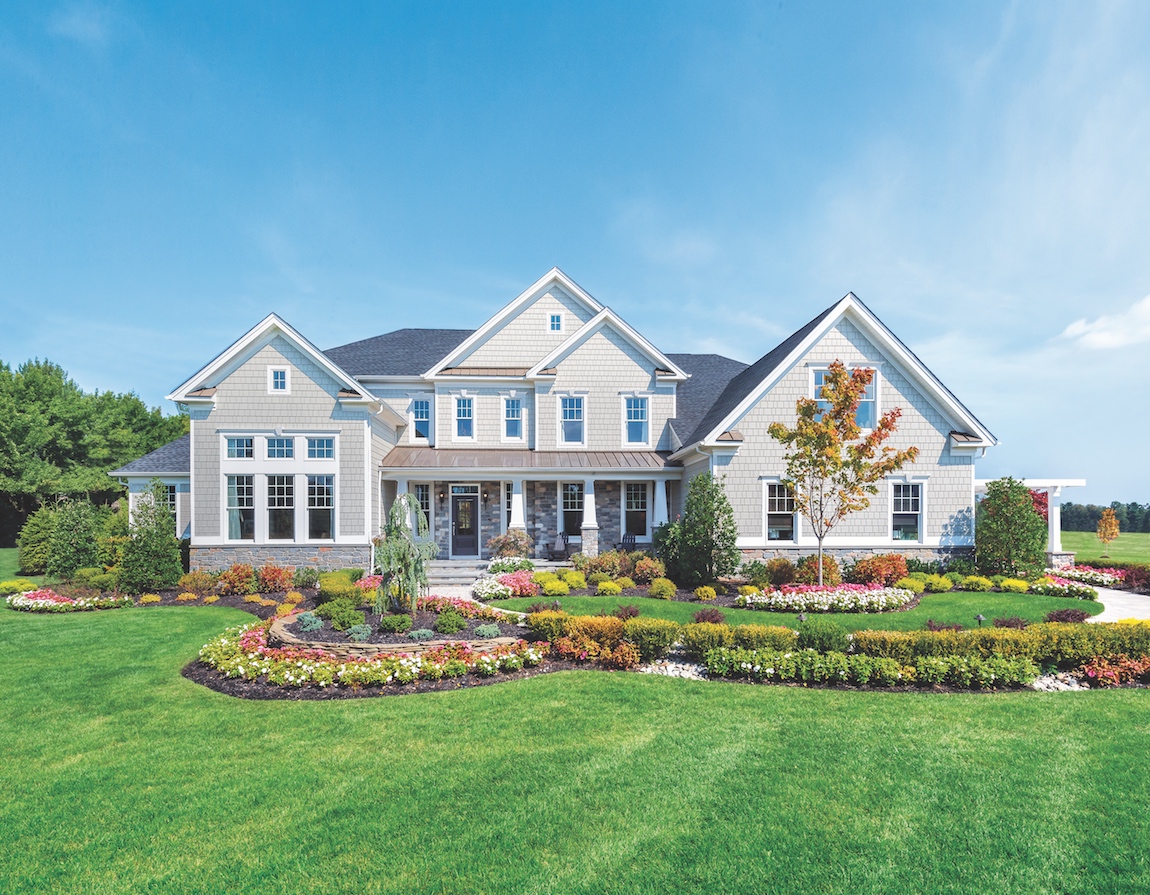 A neutral color shake Toll Brothers house with stone wainscot and terra bronze roof accents.