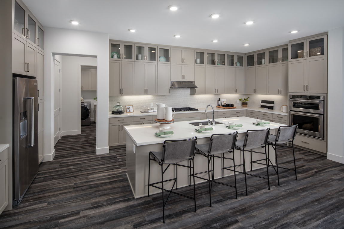 A luxury kitchen with lots of cabinets and a large island with seating. 